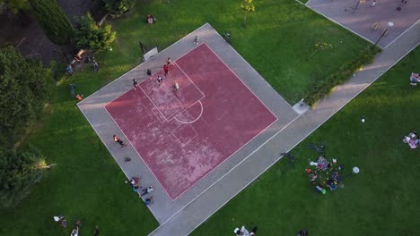 Gente-Jugando-En-Una-Cancha-De-Baloncesto-Pública-Rosa-Inmersa-En-Un-Paisaje-Verde,-Buenos-Aires-En-Argentina