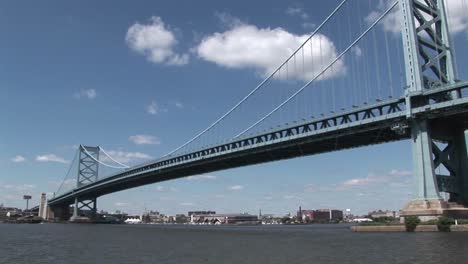 A-boat-passes-under-the-Ben-Franklin-Bridge-which-leads-to-Philadelphia-Pennsylvania-at-day