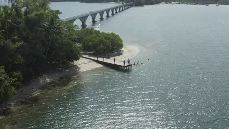 AERIAL---Bridge-and-people-on-small-dock,-Samana,-Dominican-Republic,-lowering-shot