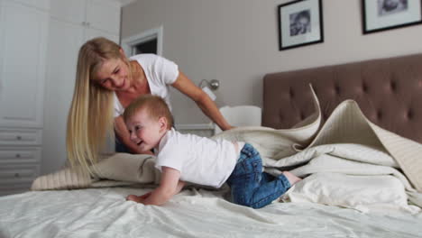 Young-mother-and-father-with-her-2-years-old-little-son-dressed-in-pajamas-are-relaxing-and-playing-in-the-bed-at-the-weekend-together,-lazy-morning,-warm-and-cozy-scene.-Pastel-colors,-selective-focus