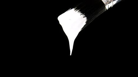 pintura cayendo del pincel contra un fondo negro 4k