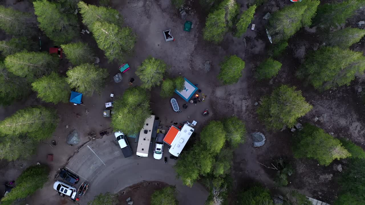 Vehicles And Tents On The Campground Surrounded By Lush Green Trees In Mammoth Lakes, California. aerial top-down