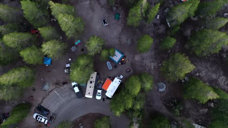 vehicles and tents on the campground surrounded by lush green trees in mammoth lakes, california. aerial top-down