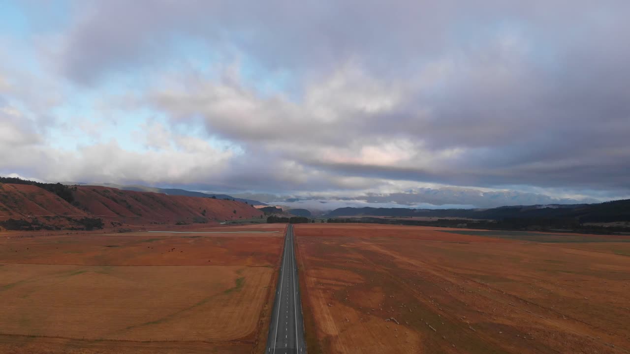 volando alto sobre una carretera remota en medio de la nada a través de pastos y campos de hierba en una tarde nublada en 4k