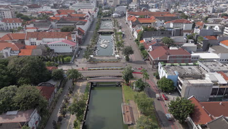 Einheimische-Fahren-über-Eine-Brücke-Im-Alten-Batavia,-Kota-Tua,-Jakarta,-Während-Eine-Drohne-Herabsteigt