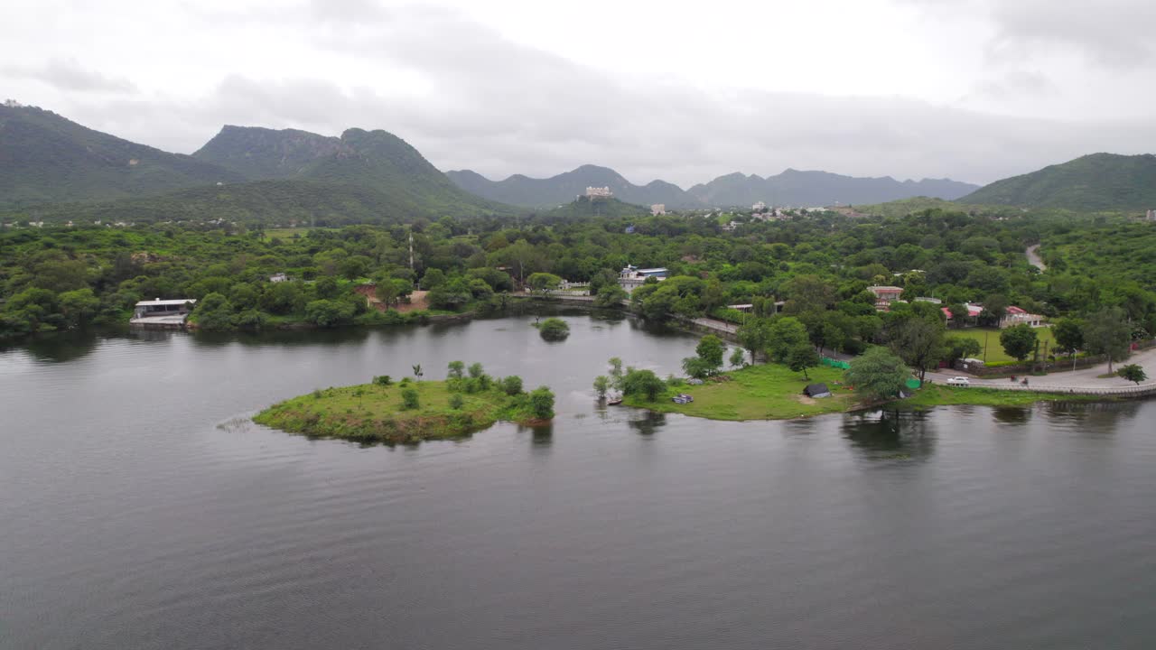 drone volando sobre el lago fateh sagar y el palacio del monzón sajjangarh en segundo plano