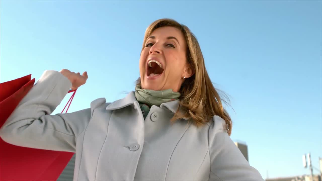 mujer feliz girando con bolsas de compras
