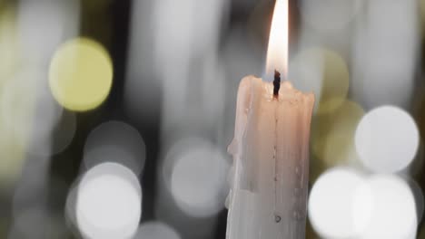 Video-of-white-candle-with-white-flame-and-copy-space-with-bokeh-on-black-background