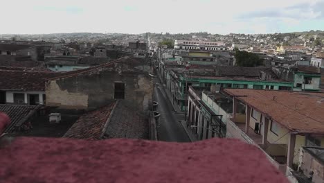 typical evening view over cuban city rooftops with a traditional vintage car driving and a person walking down the street in matanzas
