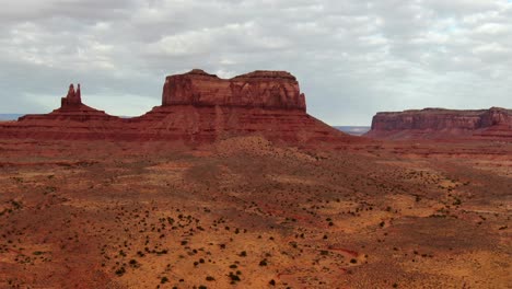 aerial approach towards massive sandstone buttes in red sand desert in arizona