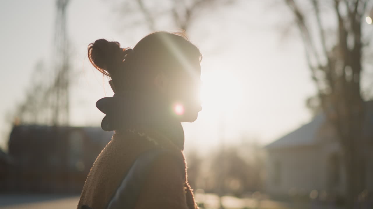 A close-up shot of a girl carrying a backpack, walking with an unhappy expression. The image captures a moment of deep contemplation and sorrow. The soft backlighting from the sunset adds a reflective