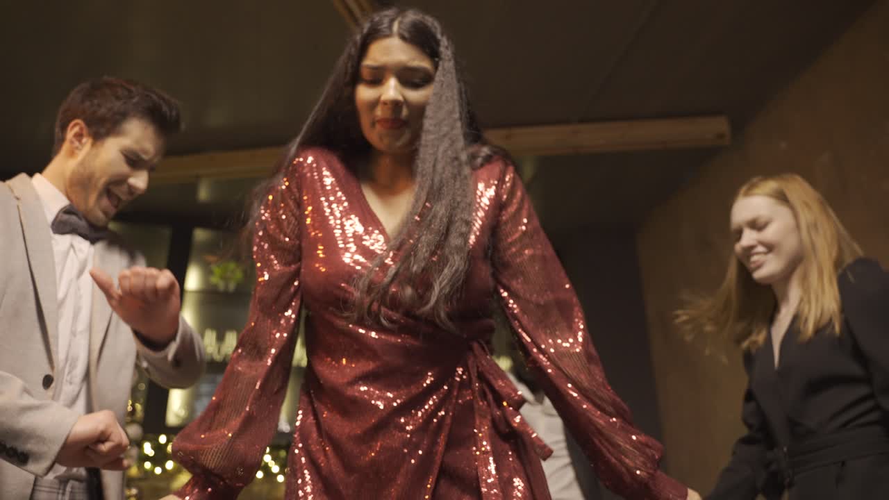 Bottom view of couple dressed in elegant clothes dance with friends at the New Year's party