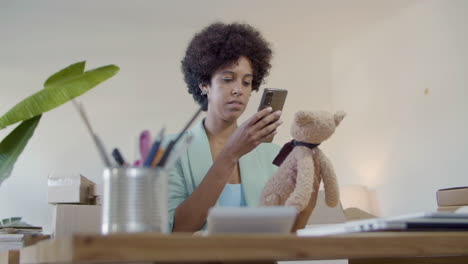 joven mujer de negocios negra tomando una foto de un oso de peluche