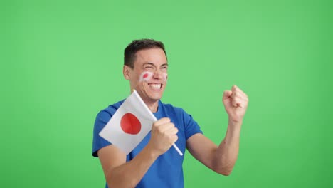 man cheering for japan waving a national flag looking away