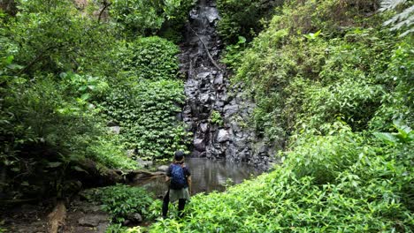 una mujer excursionista disfruta de las impresionantes vistas de un pozo de agua escondido y una cascada a lo largo de una pista turística