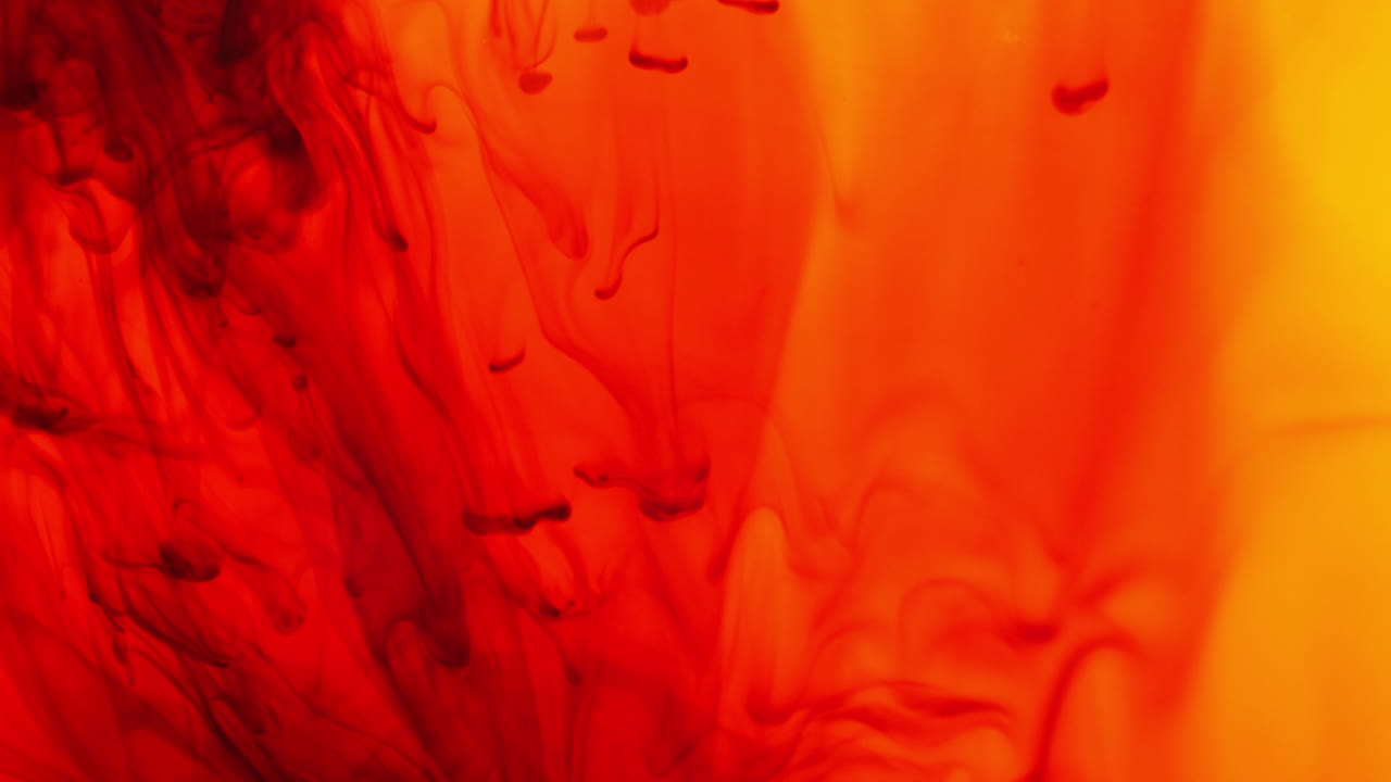 красная и желтая краска или краситель падают в воду на белом фоне, чтобы создать крутящийся красочный дымовый фон 9