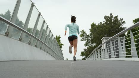 Rear-view-of-African-American-woman-running-on-a-bridge-in-the-city-4k