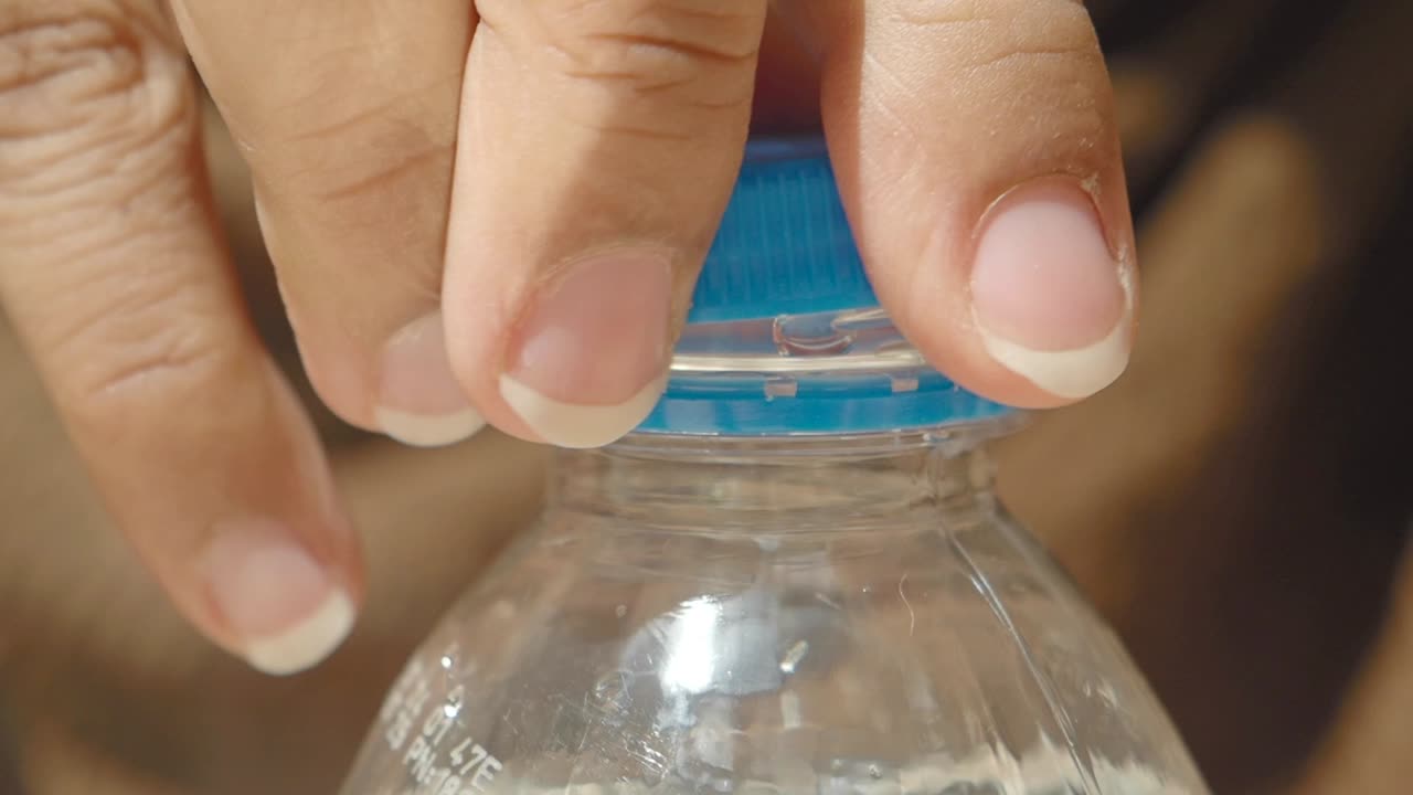 persona que abre una botella de agua de plástico