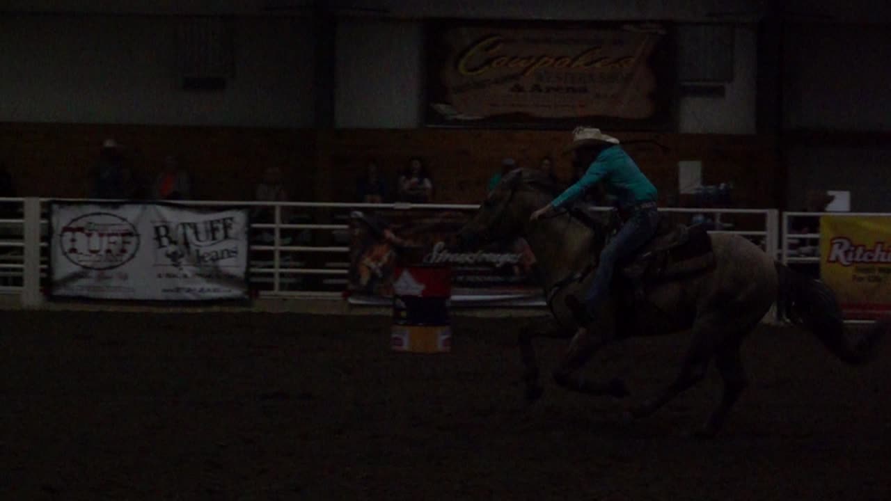 Cowgirl à cheval galopant dans une arène de barrel racing intérieure