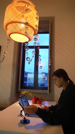mujer trabajando en una computadora portátil en casa por la noche