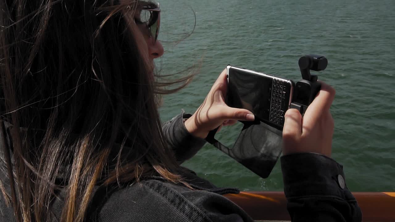 cámara lenta de video de grabación femenina con teléfono inteligente y cámara de cardán en ferry moviéndose sobre el agua