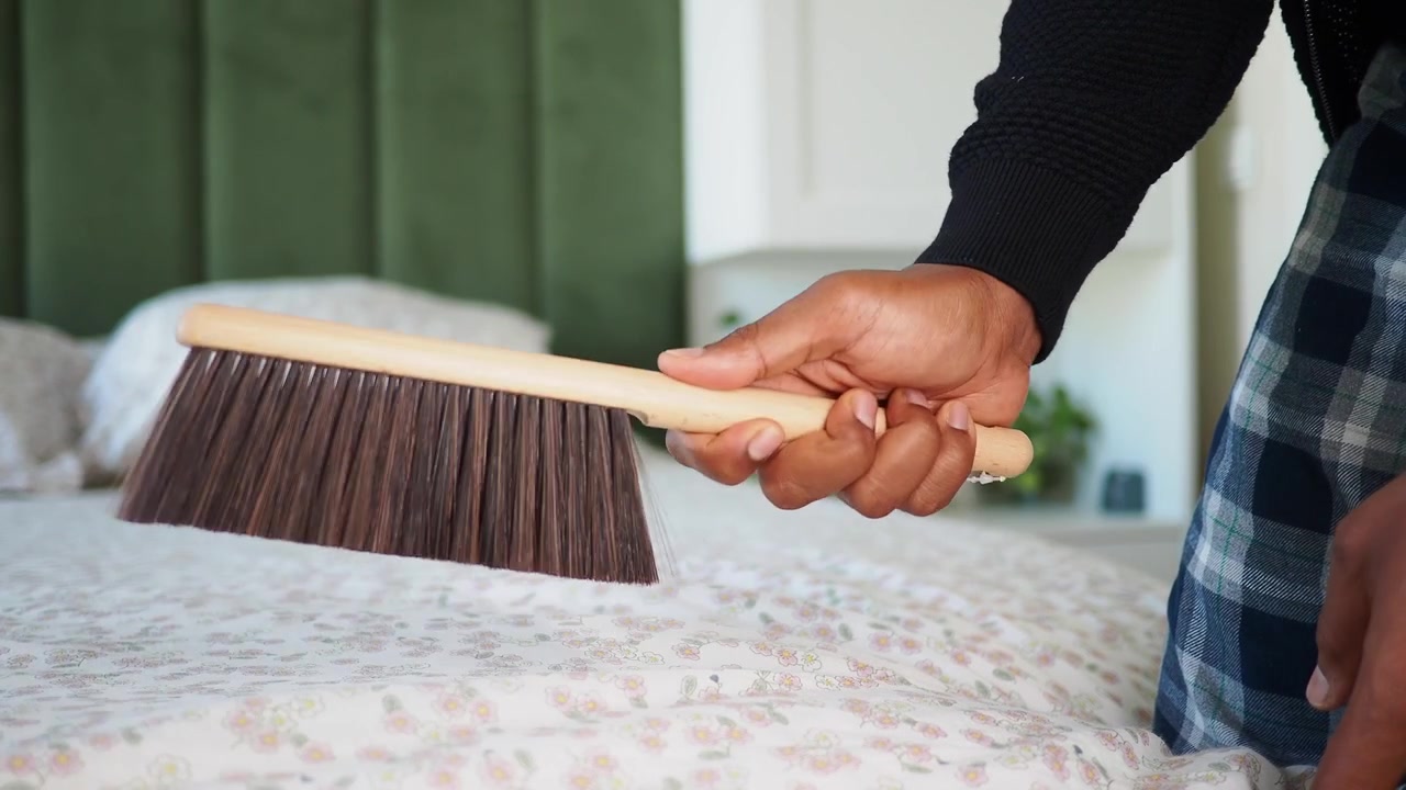 Person Cleaning Bedding with Handheld Brush