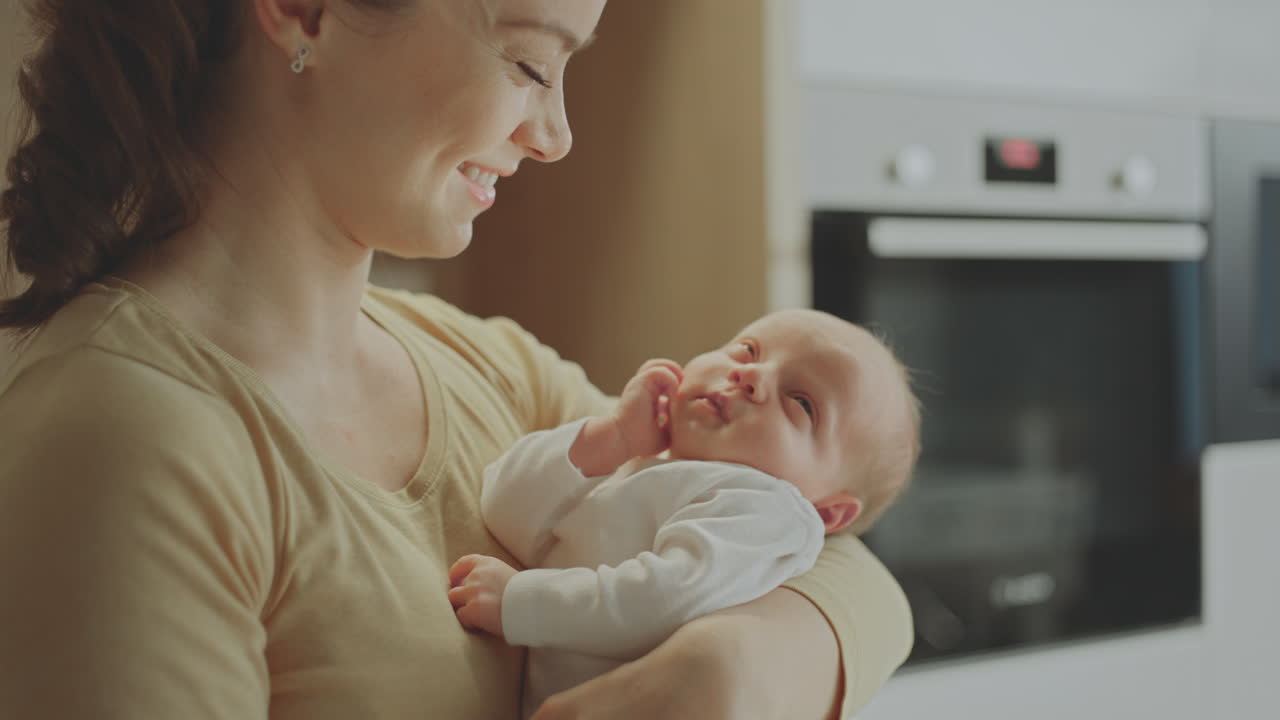 Mother holding a sleeping baby in the kitchen
