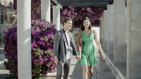 Vista-Frontal-De-Una-Pareja-Joven-Caminando-Por-Un-Callejón-Floreciente.