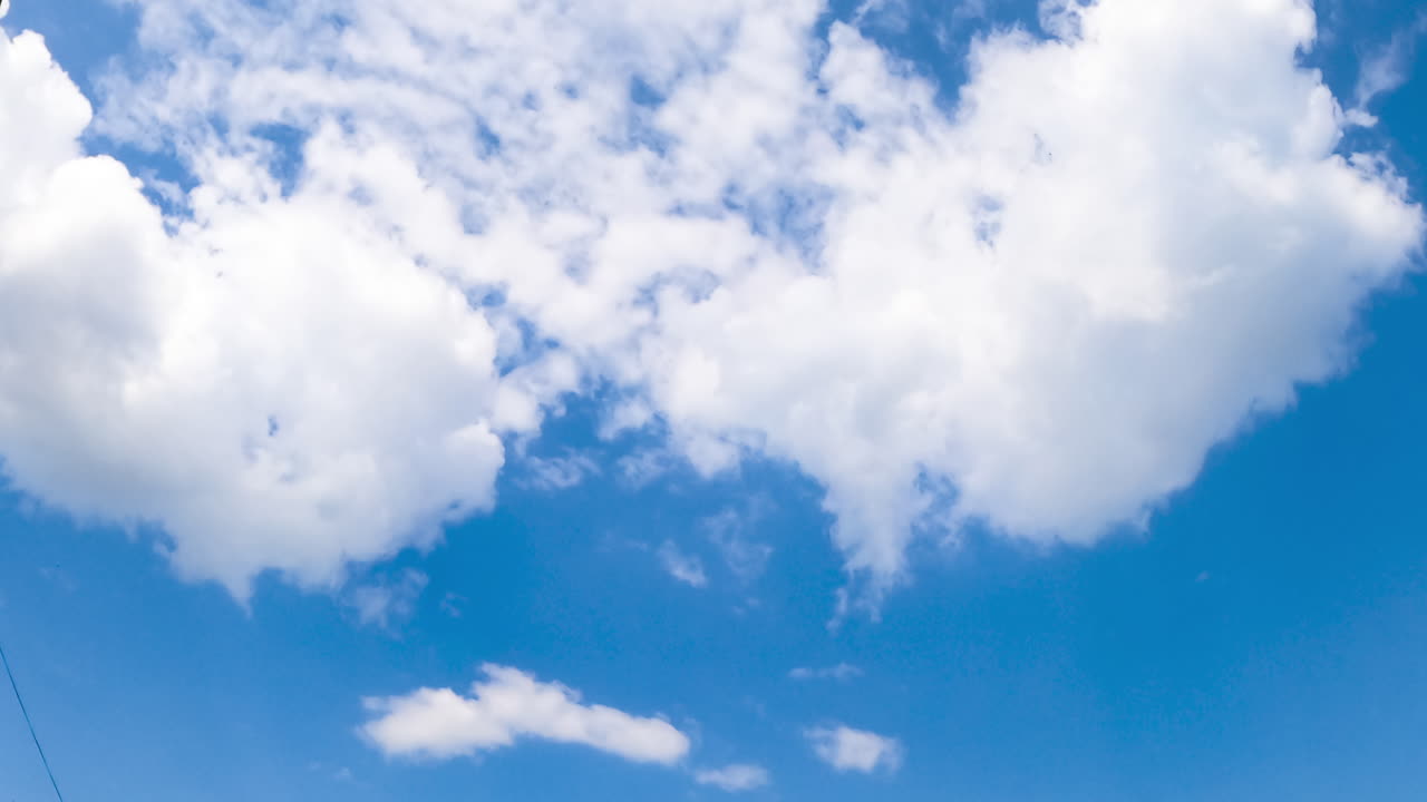 Transforming white clouds in the light blue sky. Summer skies from low angle view. Timelapse.