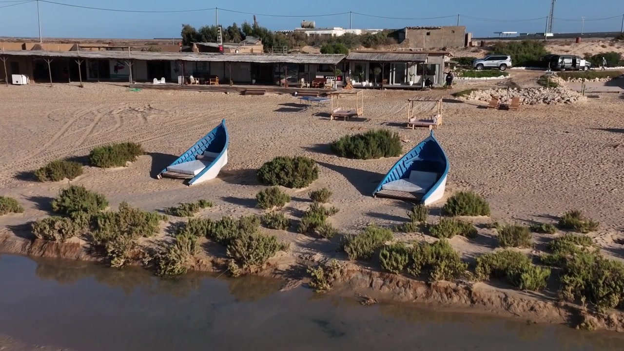 Vista aerea con drone di un centro costiero per sport acquatici con barche e infrastrutture balneari vicino a Dakhla, Marocco, ideale per progetti di viaggio e turismo