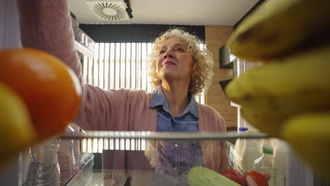 woman looking inside refrigerator full of food