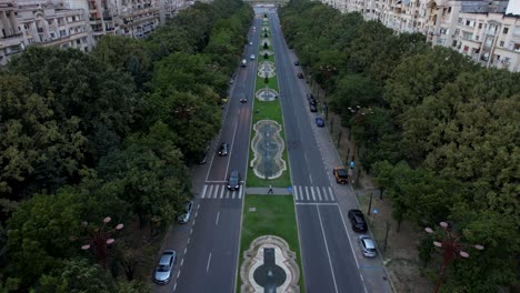 Atemberaubende-Zeitlupen-Luftaufnahme-Des-Parlamentspalastes-In-Bukarest,-Rumänien-Bei-Sonnenuntergang,-Mit-Orangefarbenem-Himmel,-üppiger-Vegetation-Und-Tanzenden-Wasserfontänen