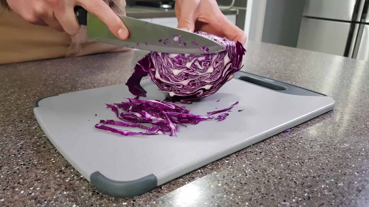 큰 칼로 부엌에서 붉은 양배추를 자르는 남자의 자른 보기