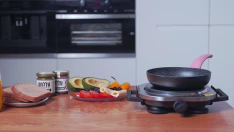 hand spraying cooking fat into frying pan, puts in egg batter for omelette, medium shot