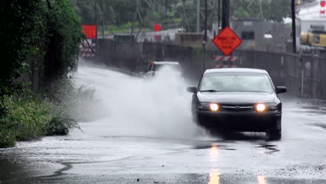 car driving through large puddle by the us steel edgar thomson steel plant in braddock, pennsylvania. raining. static shot.