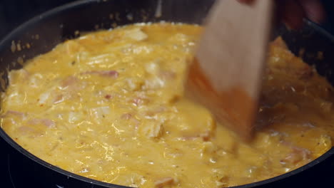 hot pan of creamy chicken curry cooks on stove, stirred with spatula