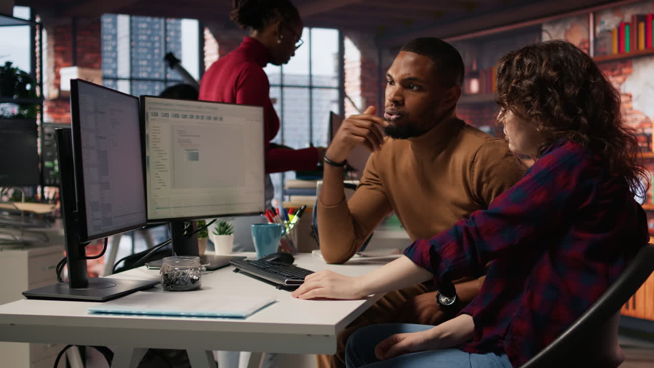 Teamworking colleagues using computer in software development agency
