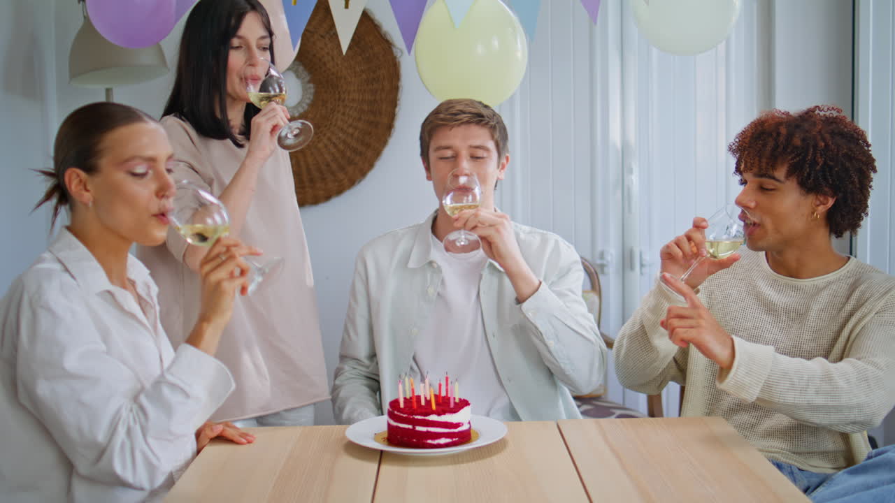 Four friends celebrating birthday clinking champagne glasses apartment closeup