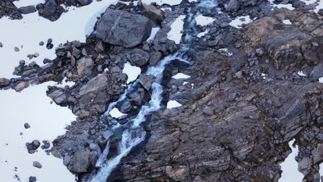 Toma-Aérea-En-órbita-De-Una-Pequeña-Cascada-Que-Fluye-A-Través-Del-Glaciar-Del-Valle-De-Buar.