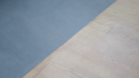 close-up of a hand reaching for a black smartphone on a wooden table