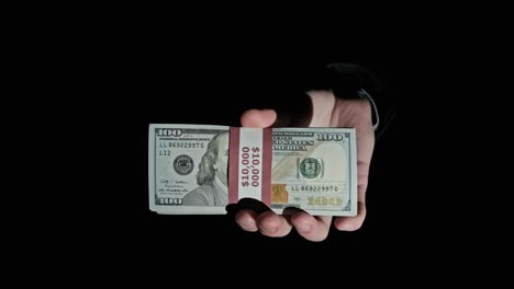 una pila de 10.000 dólares estadounidenses en paquetes en manos masculinas sobre un fondo negro.