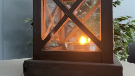 candle in wooden lantern box inside home during the day close-up for remembrance