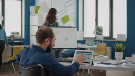 hombre de negocios con discapacidad usando computadora y tableta comparando gráficos