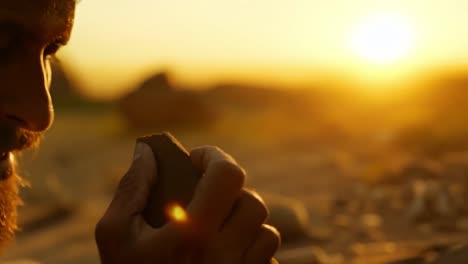 man examining an ancient stone at sunset