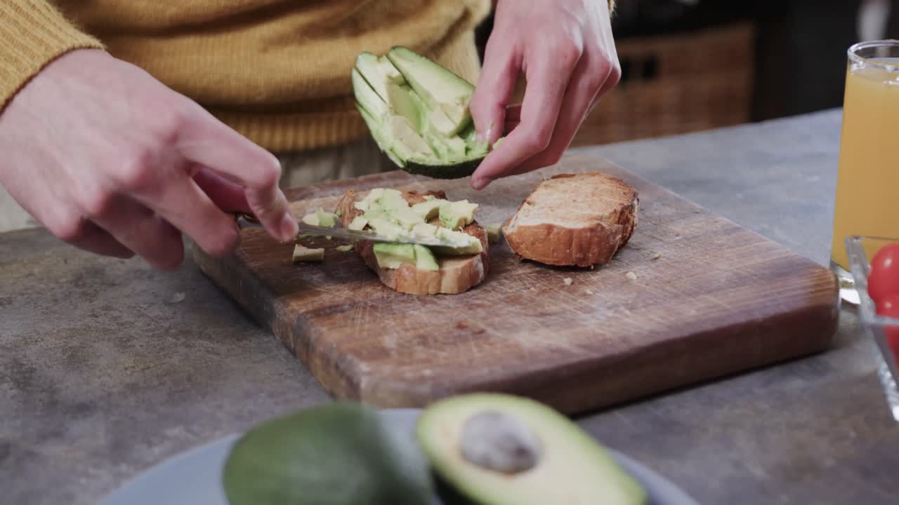 de manos hombre caucásico preparando tostadas de aguacate en la cocina, cámara lenta