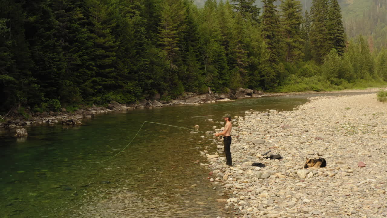Bred flygbild av en man som flugfiskar i McDonald Creek i Glacier nationalpark under en fisketur.