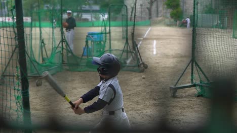 japanese kid hits the ball on baseball training, slow motion