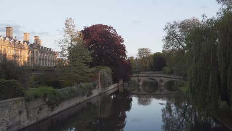 view of the river in the city centre of cambridge, england with a lot of green trees a bridge and a famous building