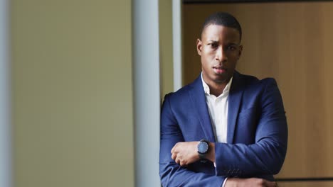 pensativo hombre de negocios afroamericano de pie junto a la ventana en una oficina moderna