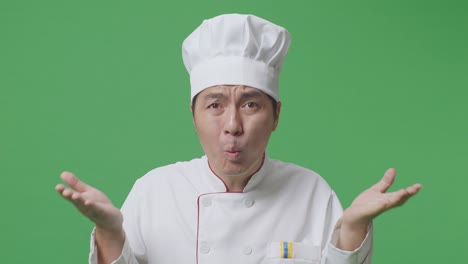 close up of wondering asian man chef saying why and standing doubtfully in the green screen background studio